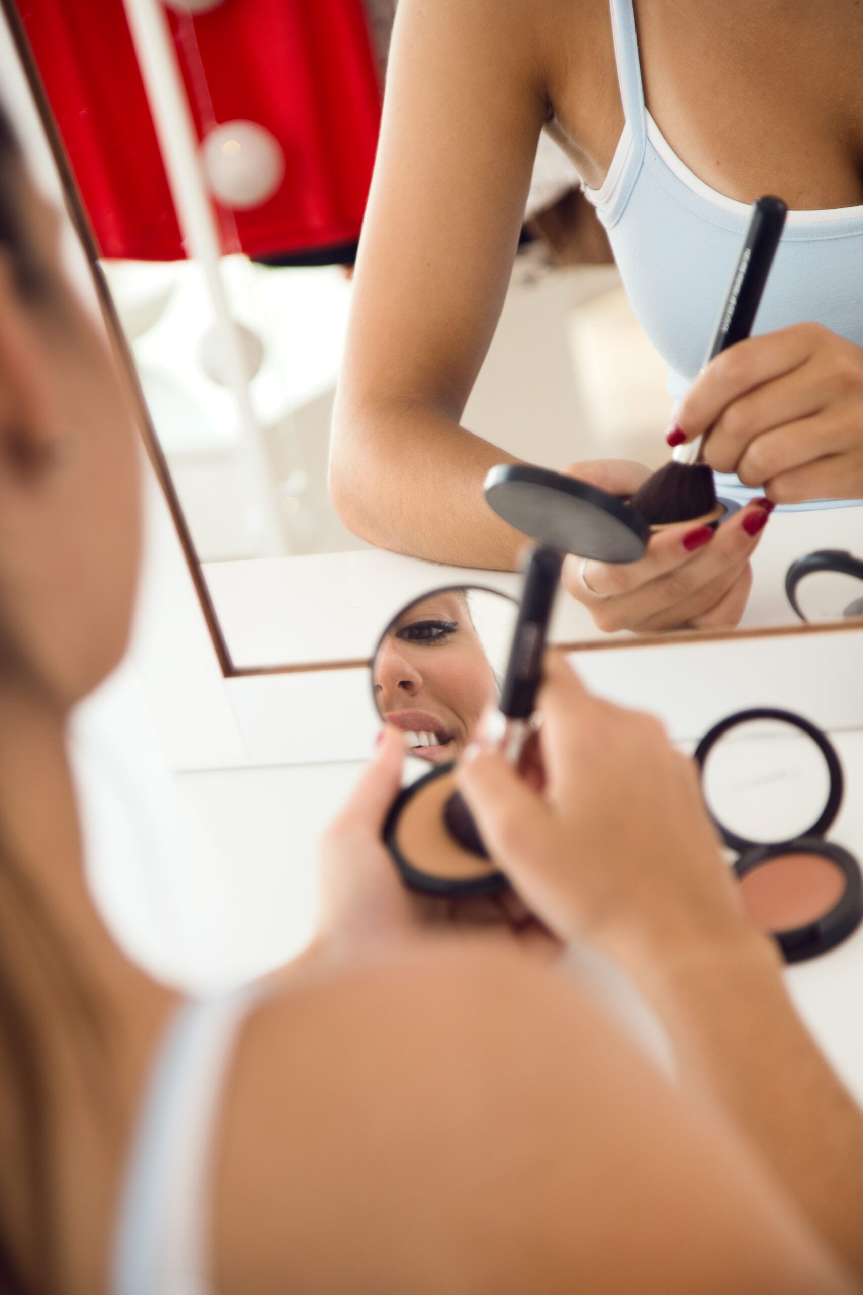 Portrait of beautiful young woman making make-up near mirror at home.